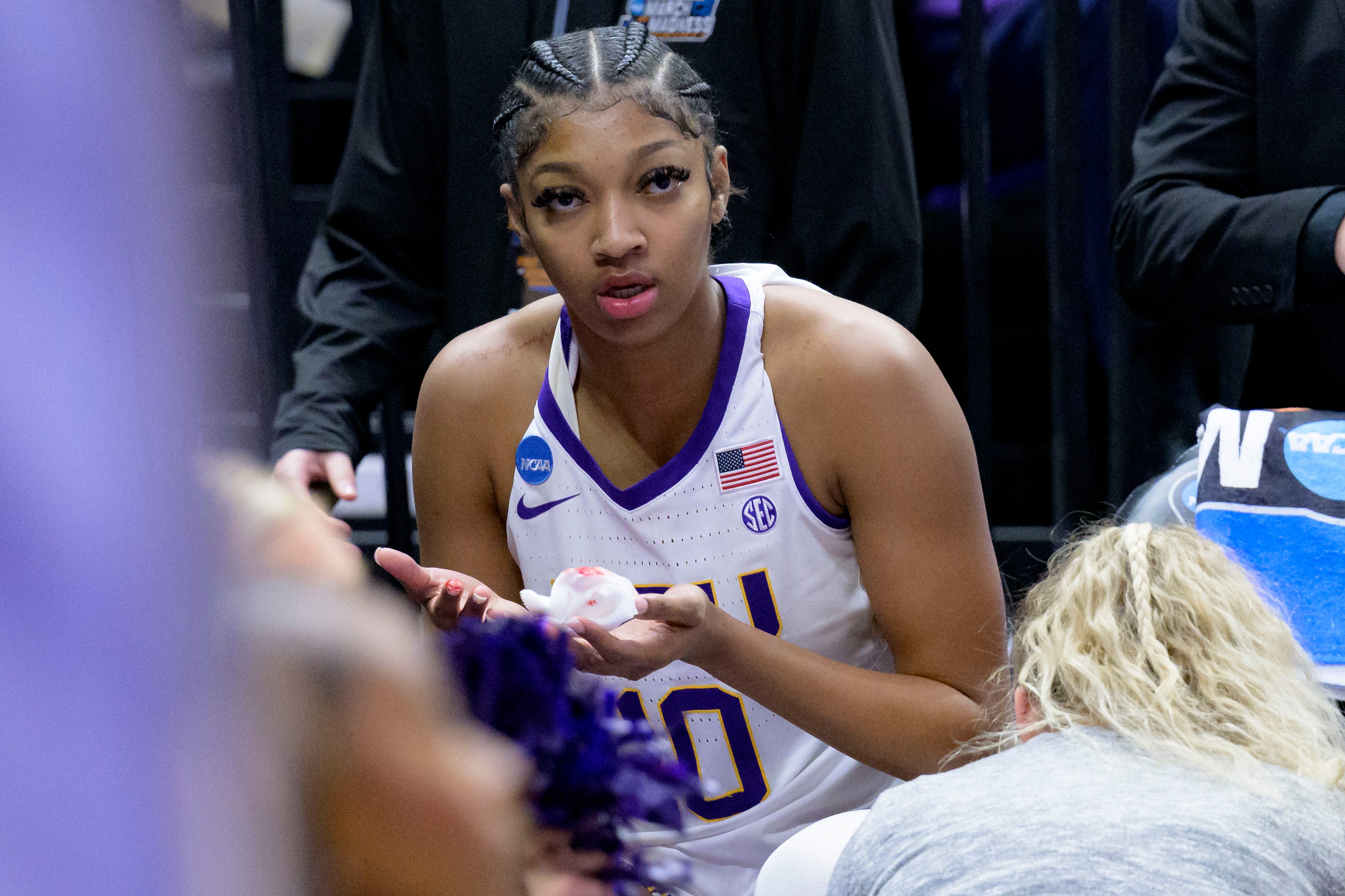 LSU forward Angel Reese (10) receives treatment after being hit on the mouth during the first half of the team's second-round college basketball game against Michigan in the women's NCAA Tournament in Baton Rouge, La., Sunday, March 19, 2023. (AP Photo/Matthew Hinton)